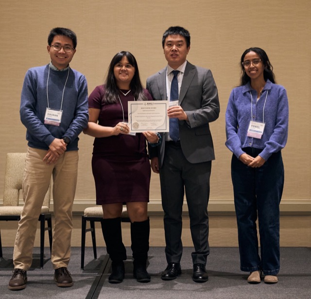 An award recipient holding a certificate on stage with organizers