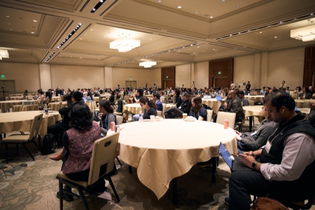 Attendees seated at round tables in the main hall