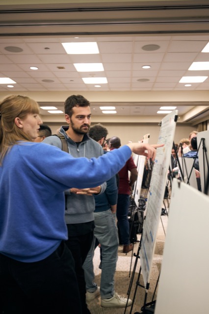 A presenter explaining a poster to attendees